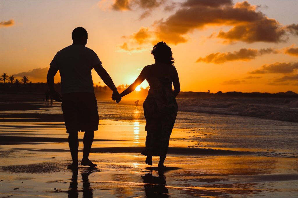 couple standing on body of water during golden hour