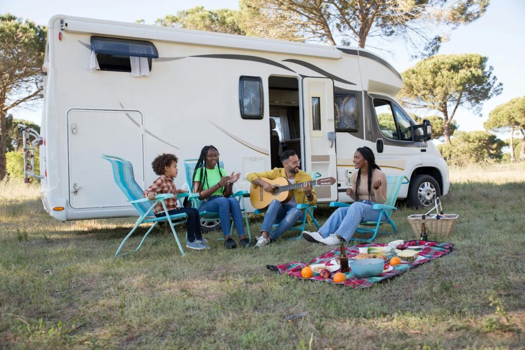 Teens Travel - A family relaxing outdoors with a picnic and guitar by their camper, enjoying a sunny summer day in Portugal. 