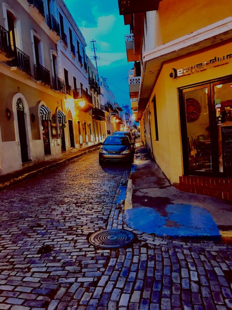 Scenic view of a historic cobblestone street in San Juan, Puerto Rico, illuminated at dusk.